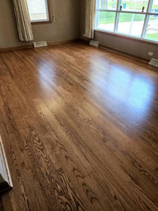 A living room with hardwood floors and a large window.