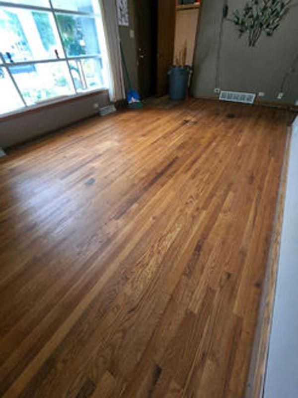 A living room with a wooden floor and a window.