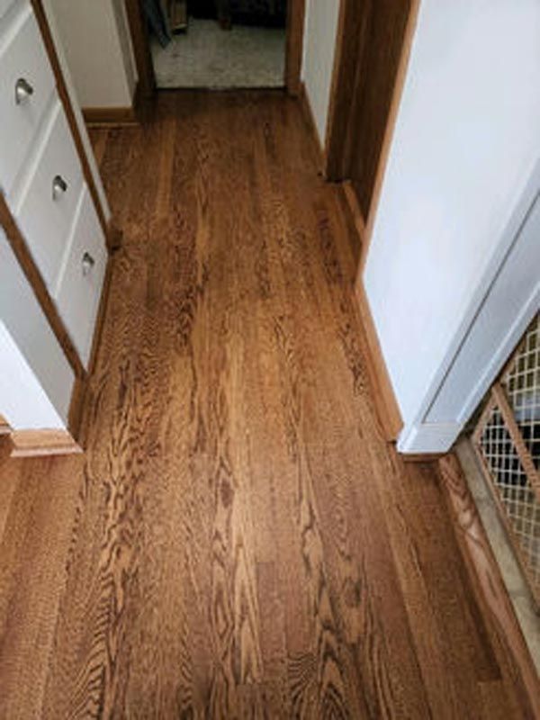 A hallway with hardwood floors and white walls in a house.