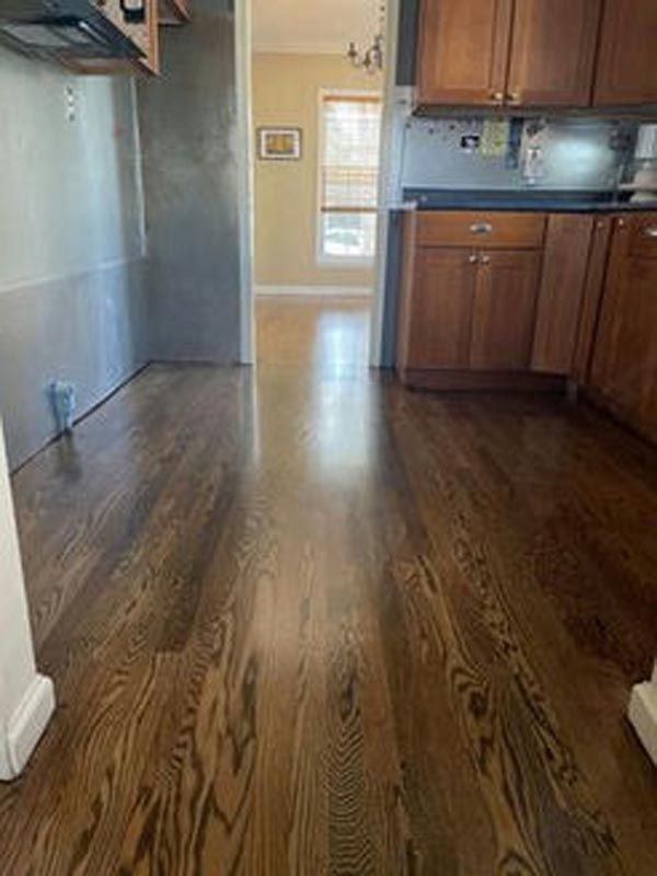 A kitchen with hardwood floors and wooden cabinets.