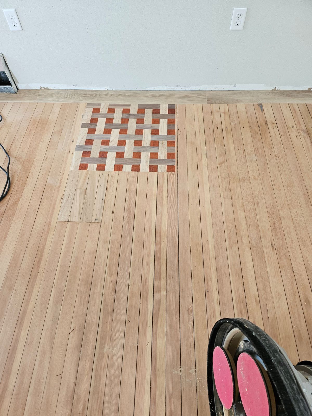 A person is standing on a wooden floor with a stencil on it