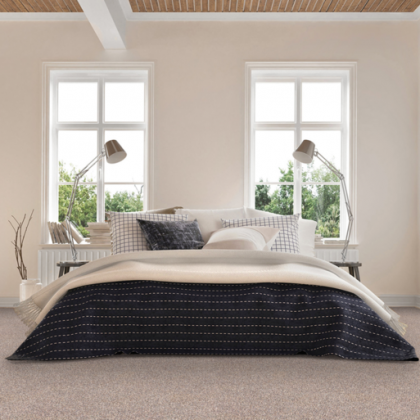 A bedroom with a bed , two lamps , and two windows.