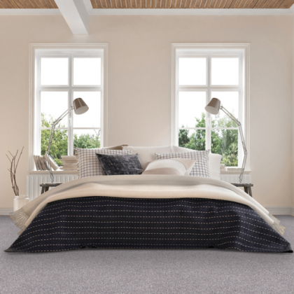 A bedroom with a bed , two lamps , and two windows.