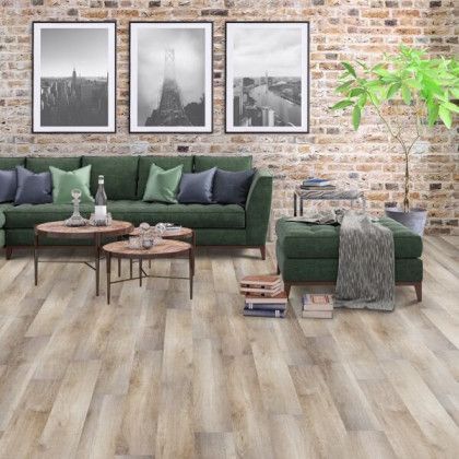 A living room with a green couch , two coffee tables , and a brick wall.