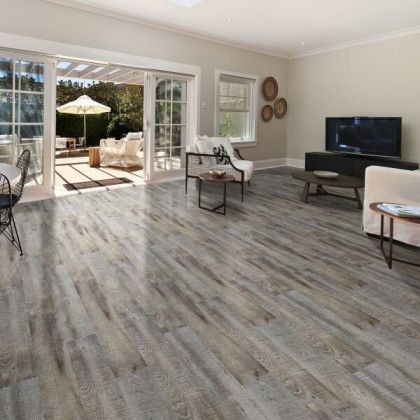 A living room with hardwood floors , a couch , chairs , tables and a television.
