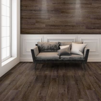 There is a couch in the middle of the room with a wooden floor.