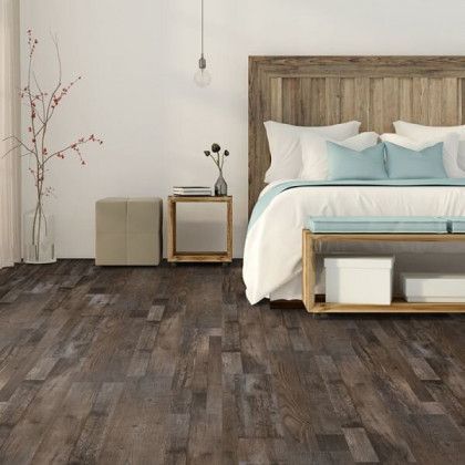 A bedroom with hardwood floors and a bed with a wooden headboard.