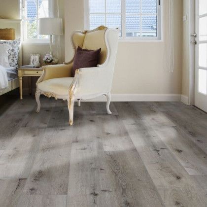A living room with hardwood floors , a chair and a bed.