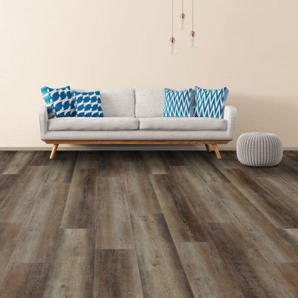A living room with a couch , ottoman , and hardwood floor.
