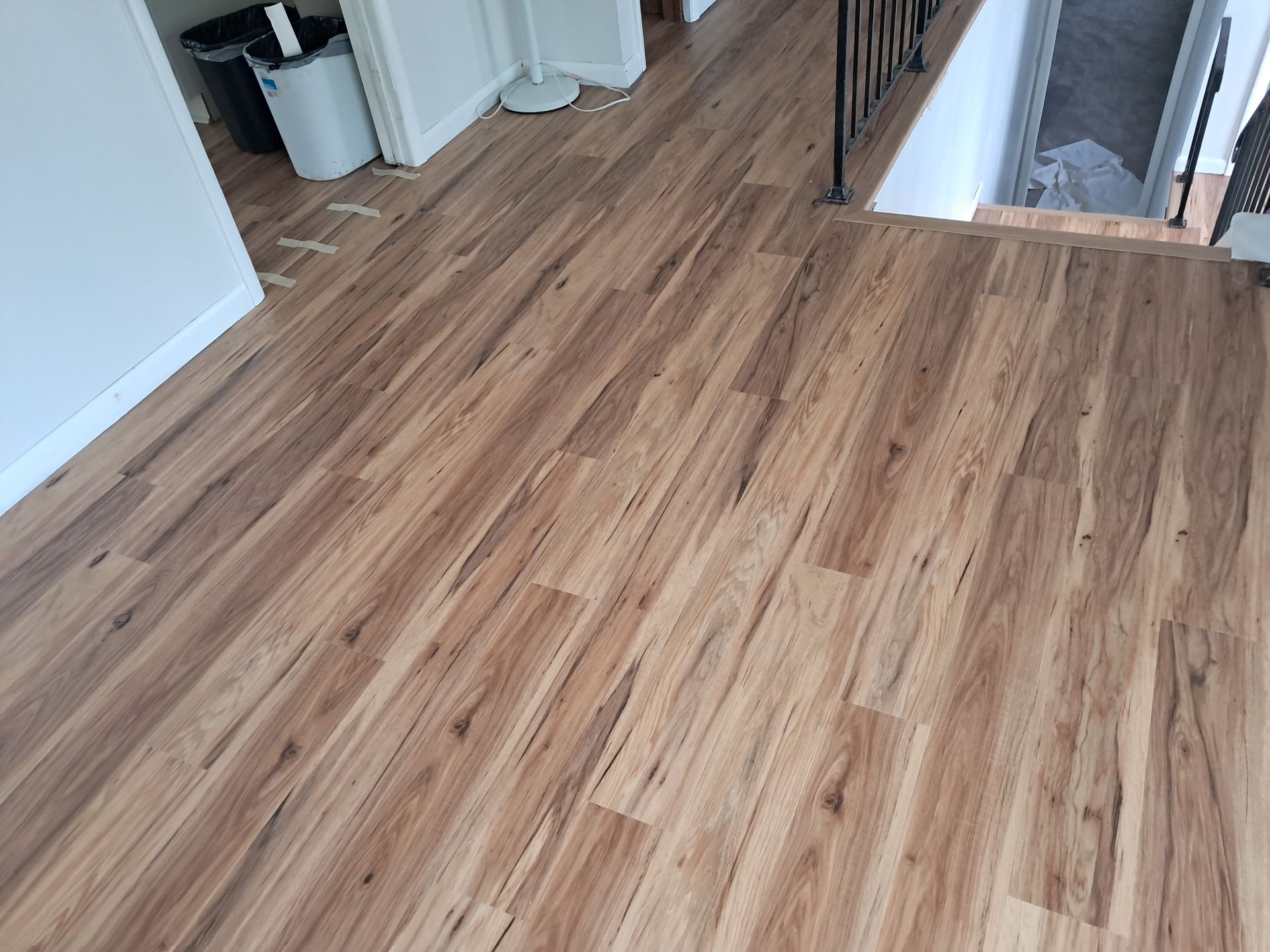 A wooden floor in a hallway next to a staircase