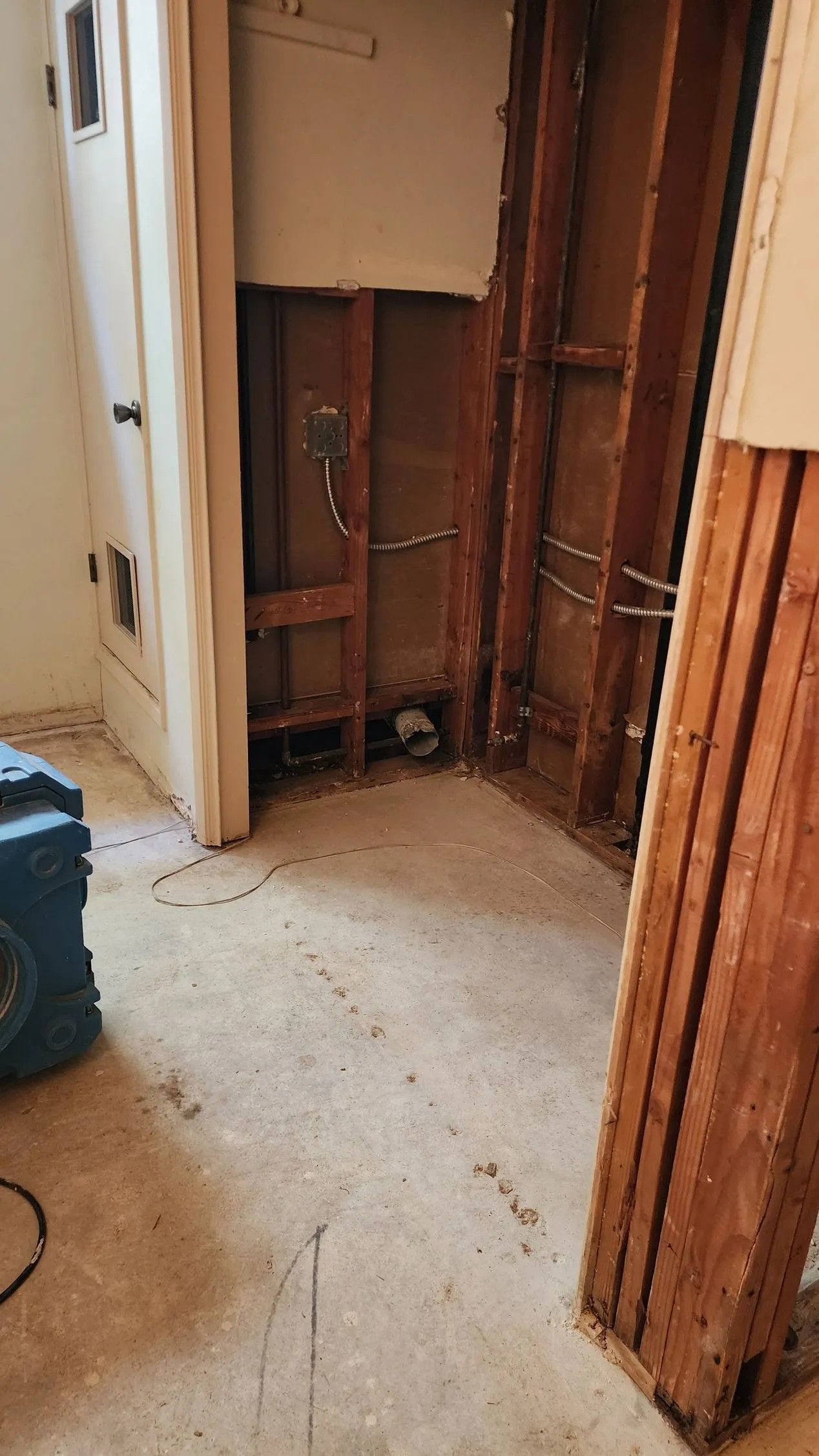 Bathroom gutted for repairs; exposed wall studs, plumbing, and debris on floor.