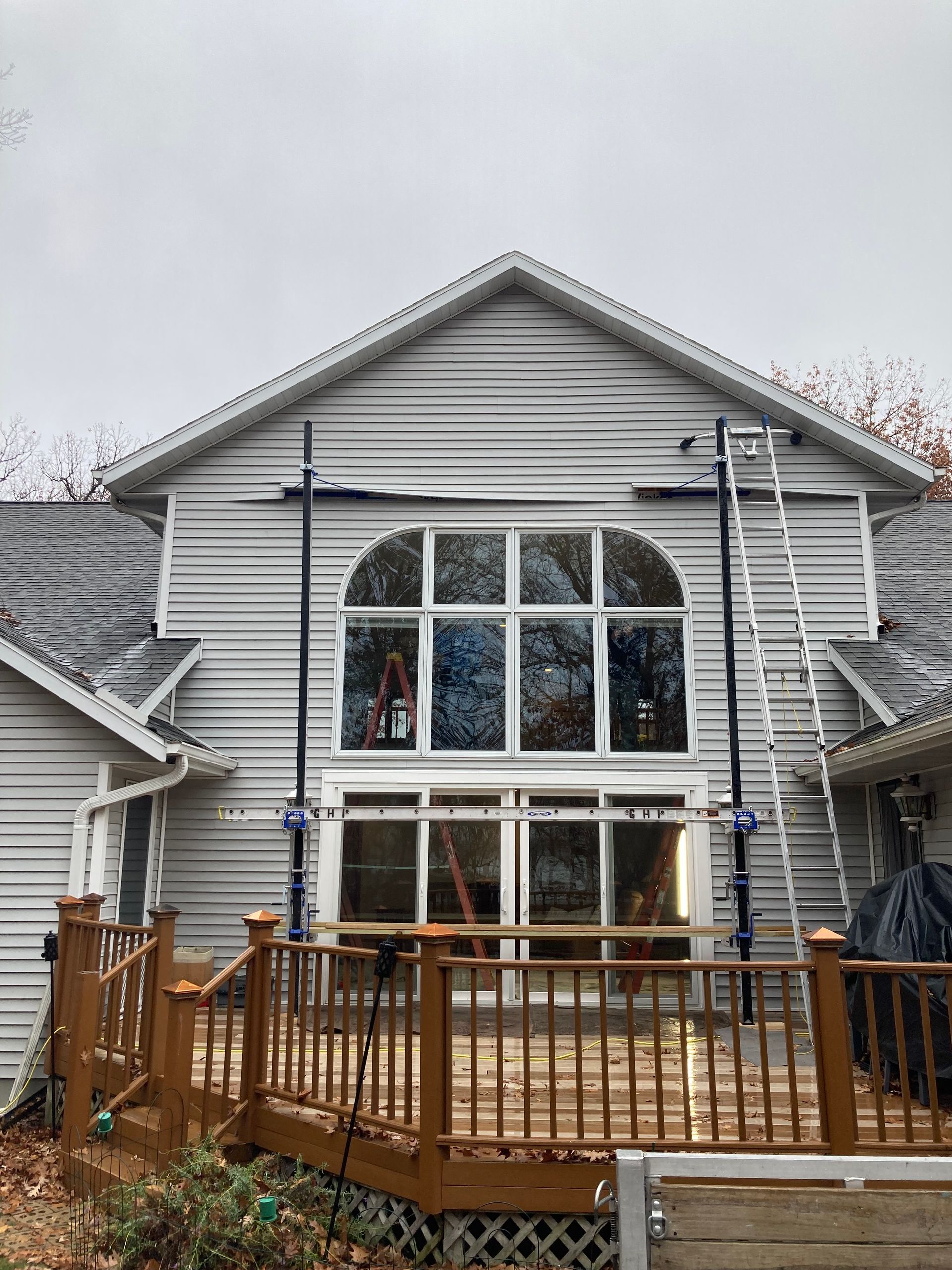 Two-story gray house with large arched windows and a wooden deck in front