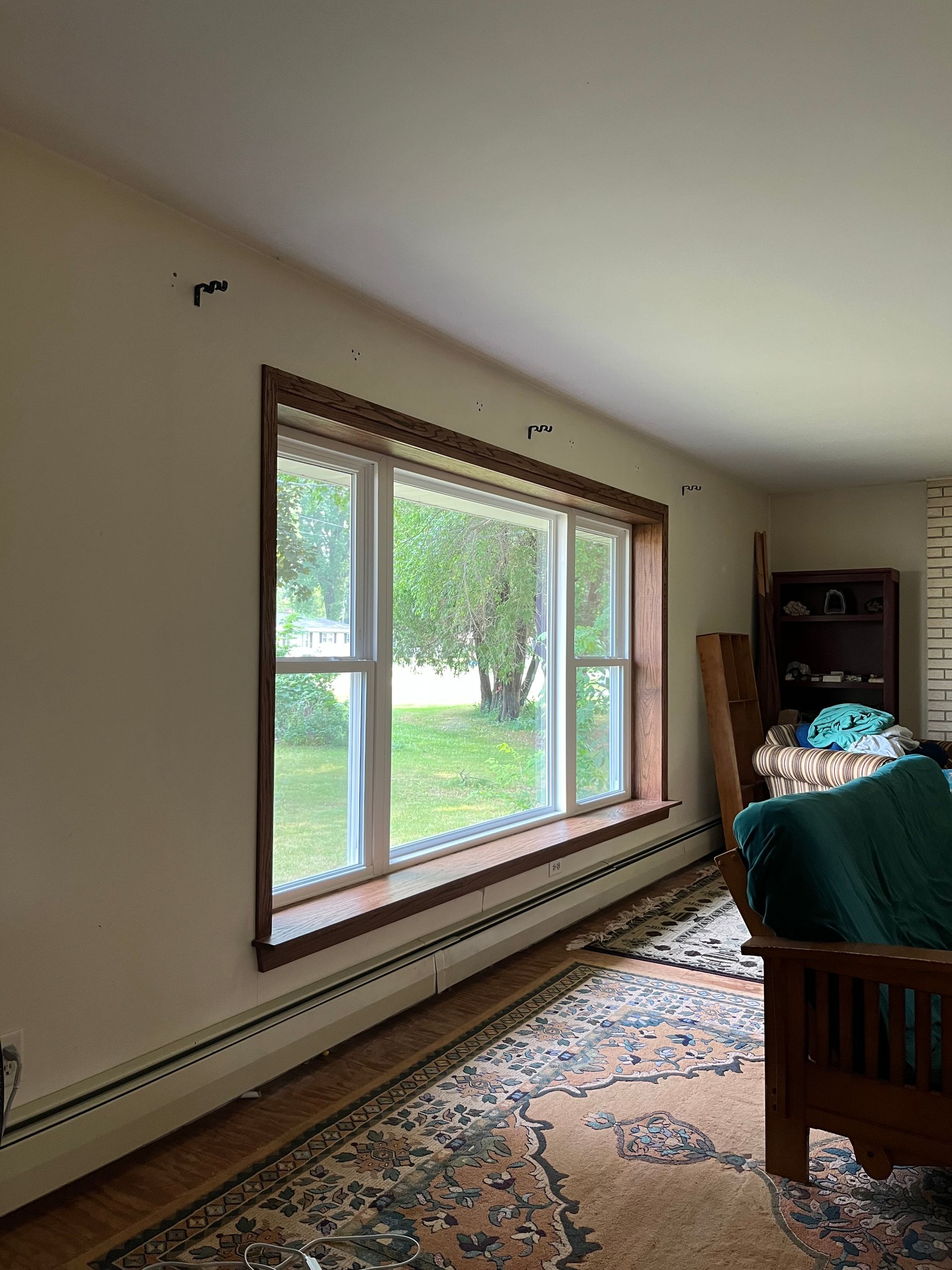Living room with large window, patterned rug, and a green sofa by the wall