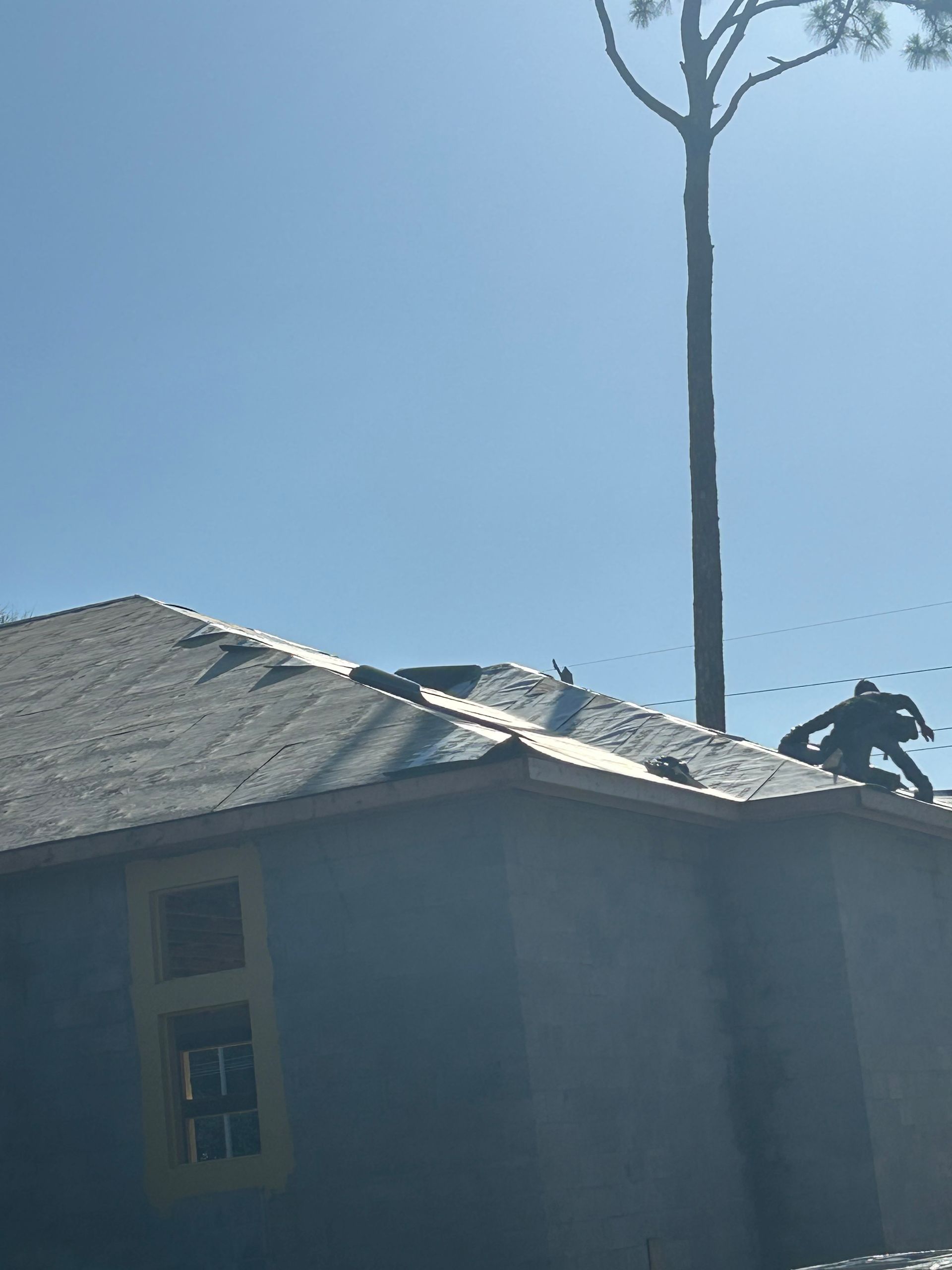 Roof under repair with workers on a house beneath a clear blue sky