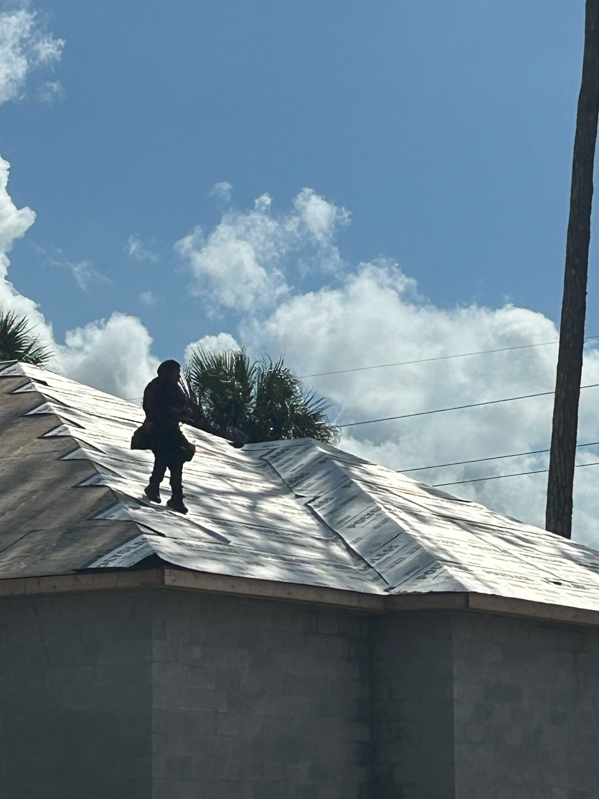 Person standing on a silver metal roof under a partly cloudy sky.
