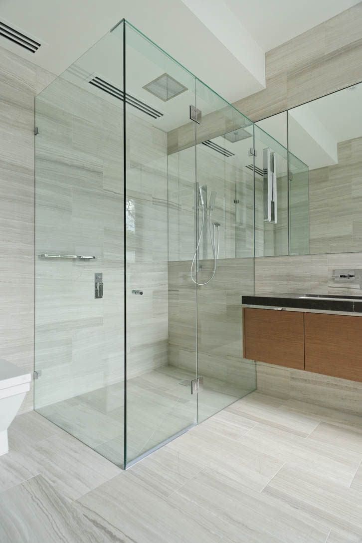 Modern bathroom with glass shower enclosure, large mirror, and floating vanity with wood cabinets