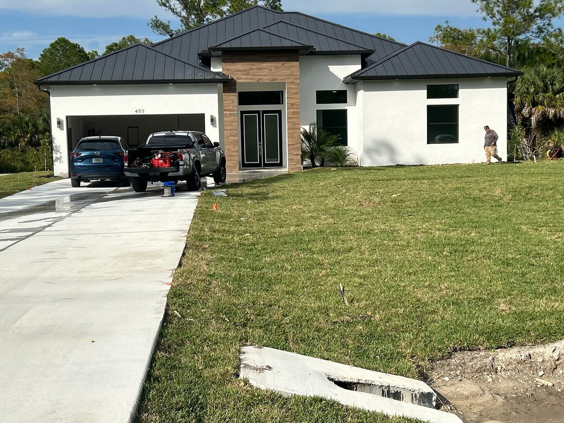 Modern single-story house with two cars in the garage, driveway, and a large front lawn