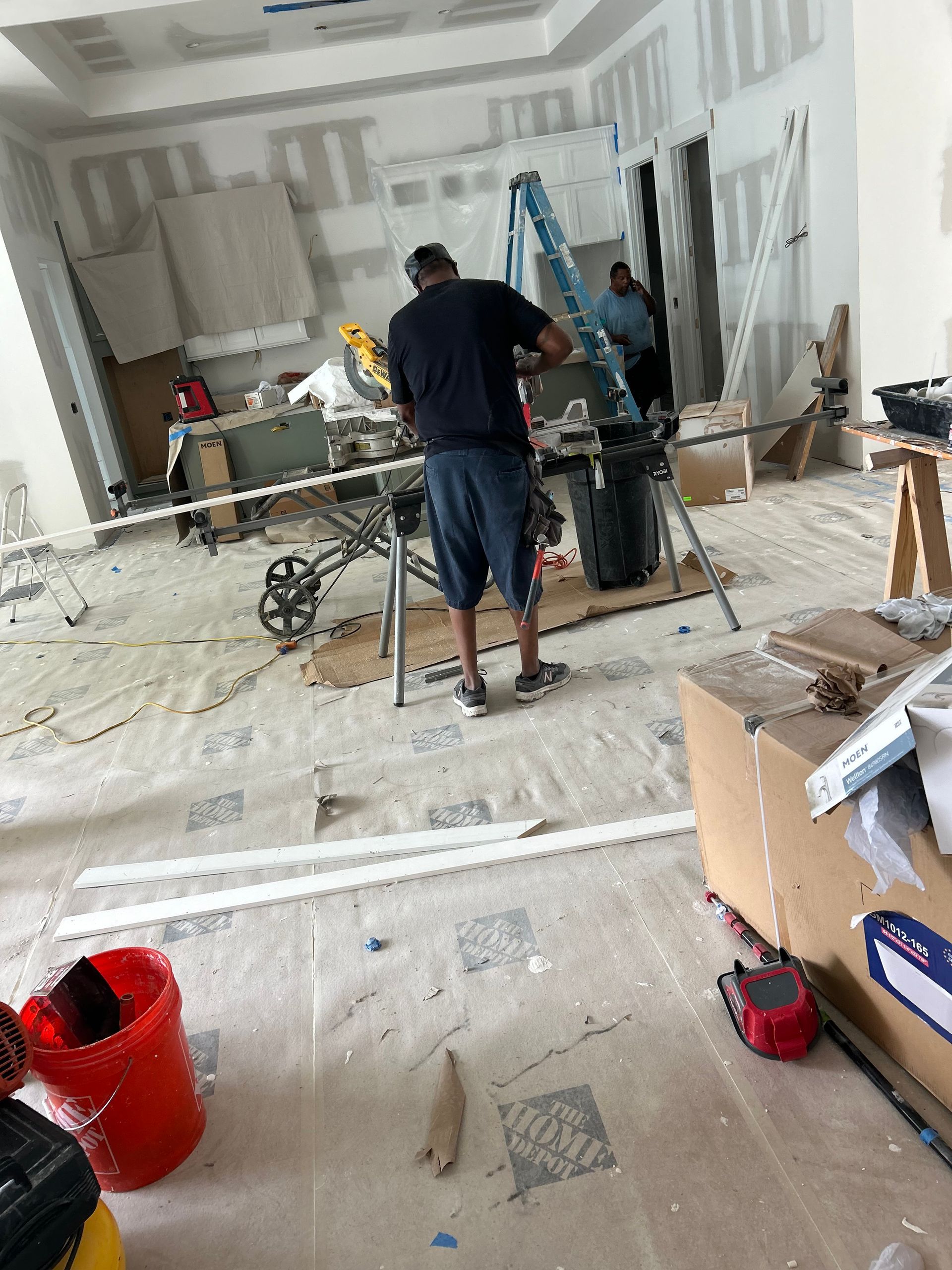Construction workers in a dusty room with tools, ladders, and scattered debris during renovation.