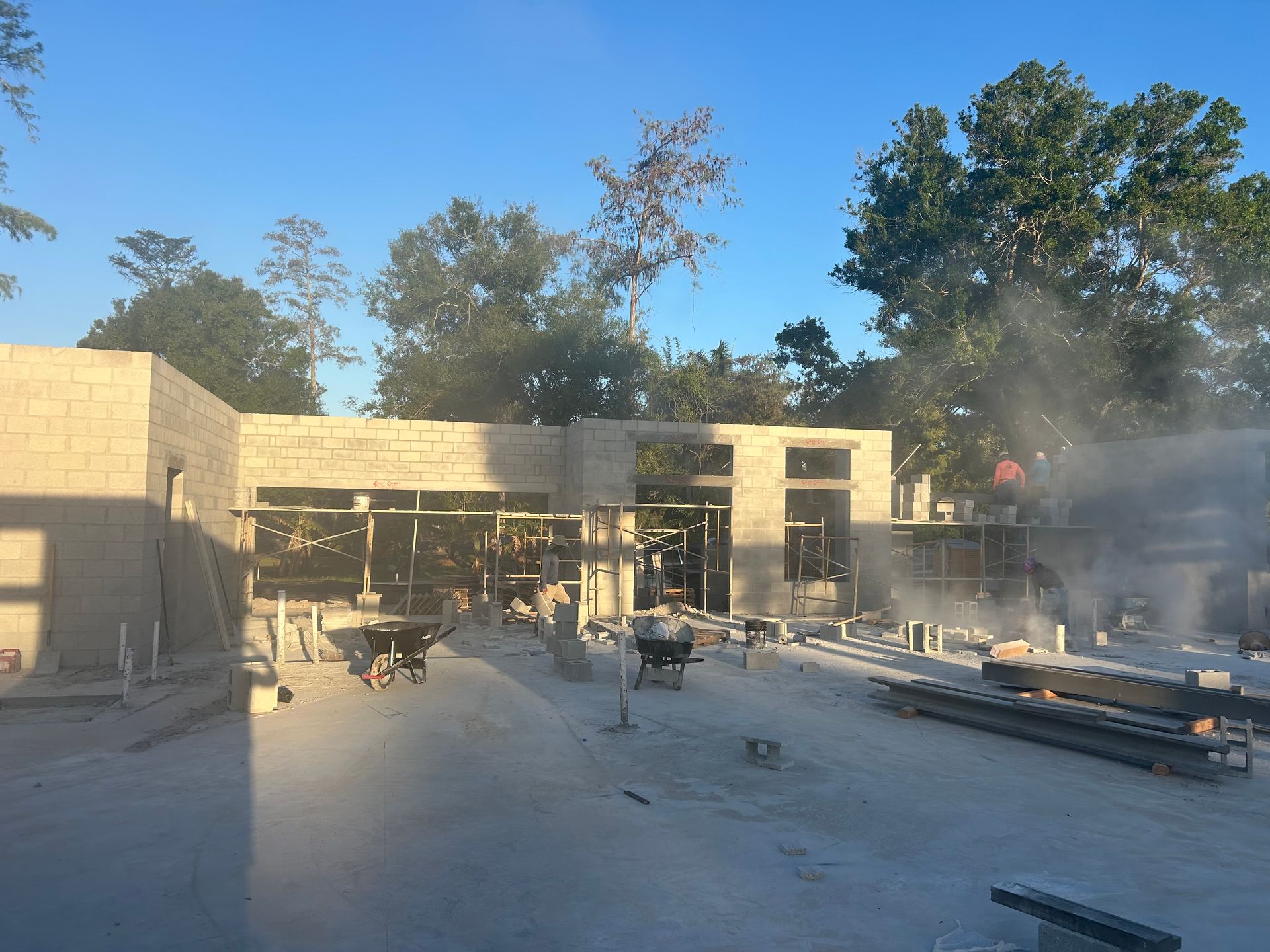 Construction site with unfinished building, scattered materials, and dust in bright sunlight
