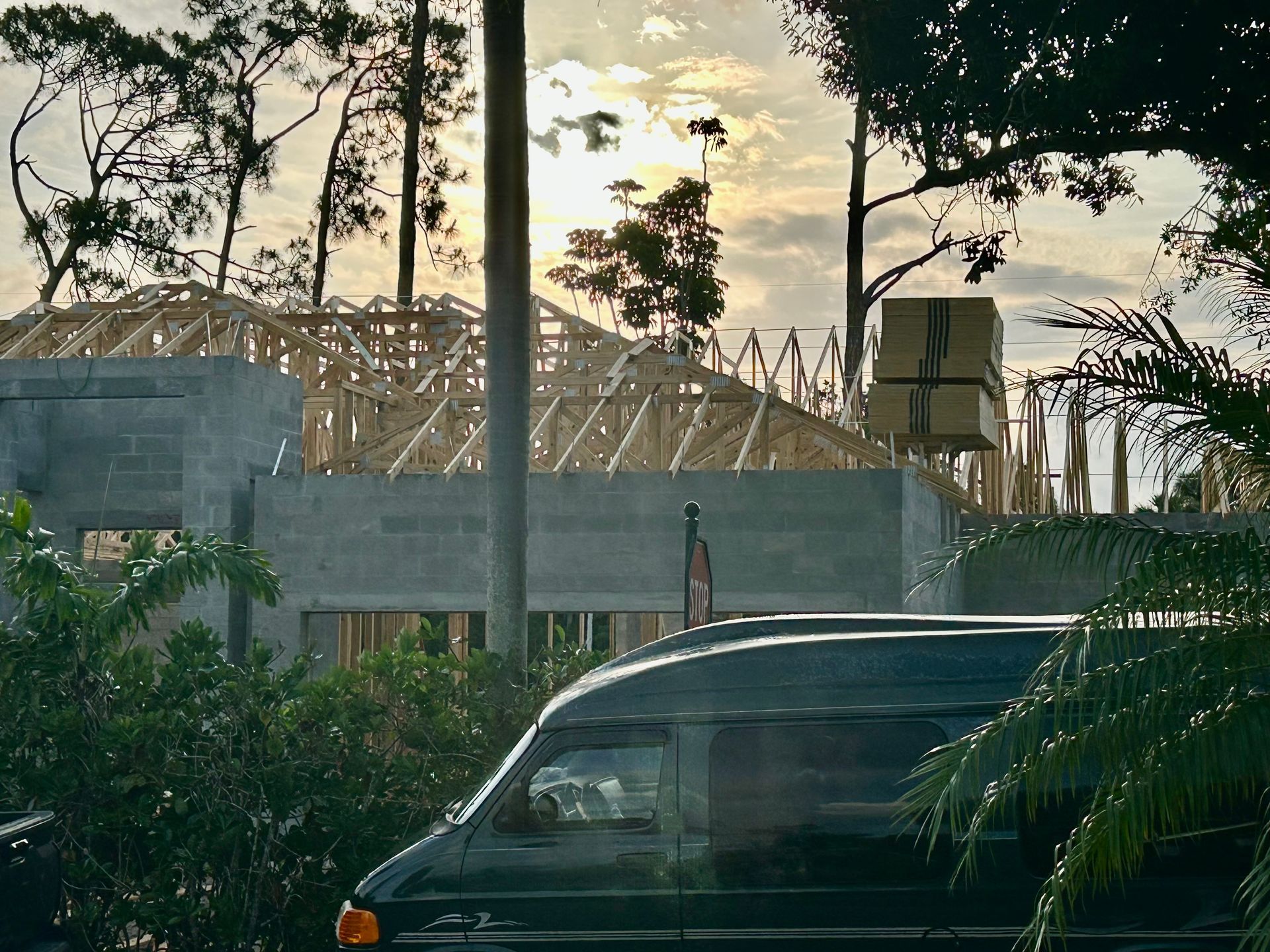Parked black SUV beside a construction site with trees silhouetted at sunset