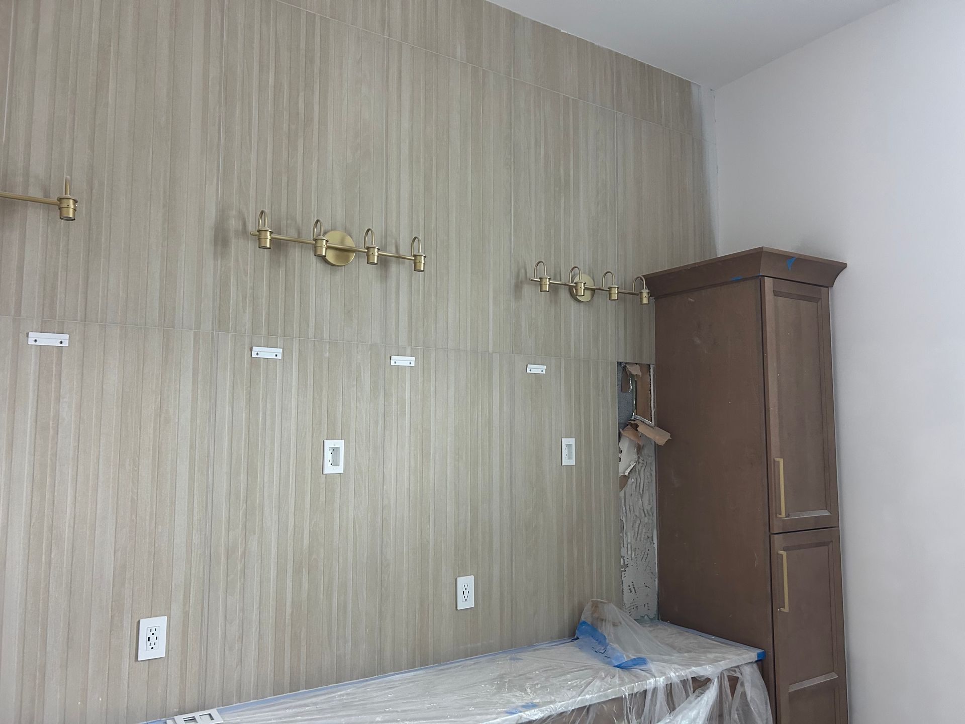 Small bedroom with striped wallpaper, wall sconces, bed edge, and tall wooden wardrobe in the corner