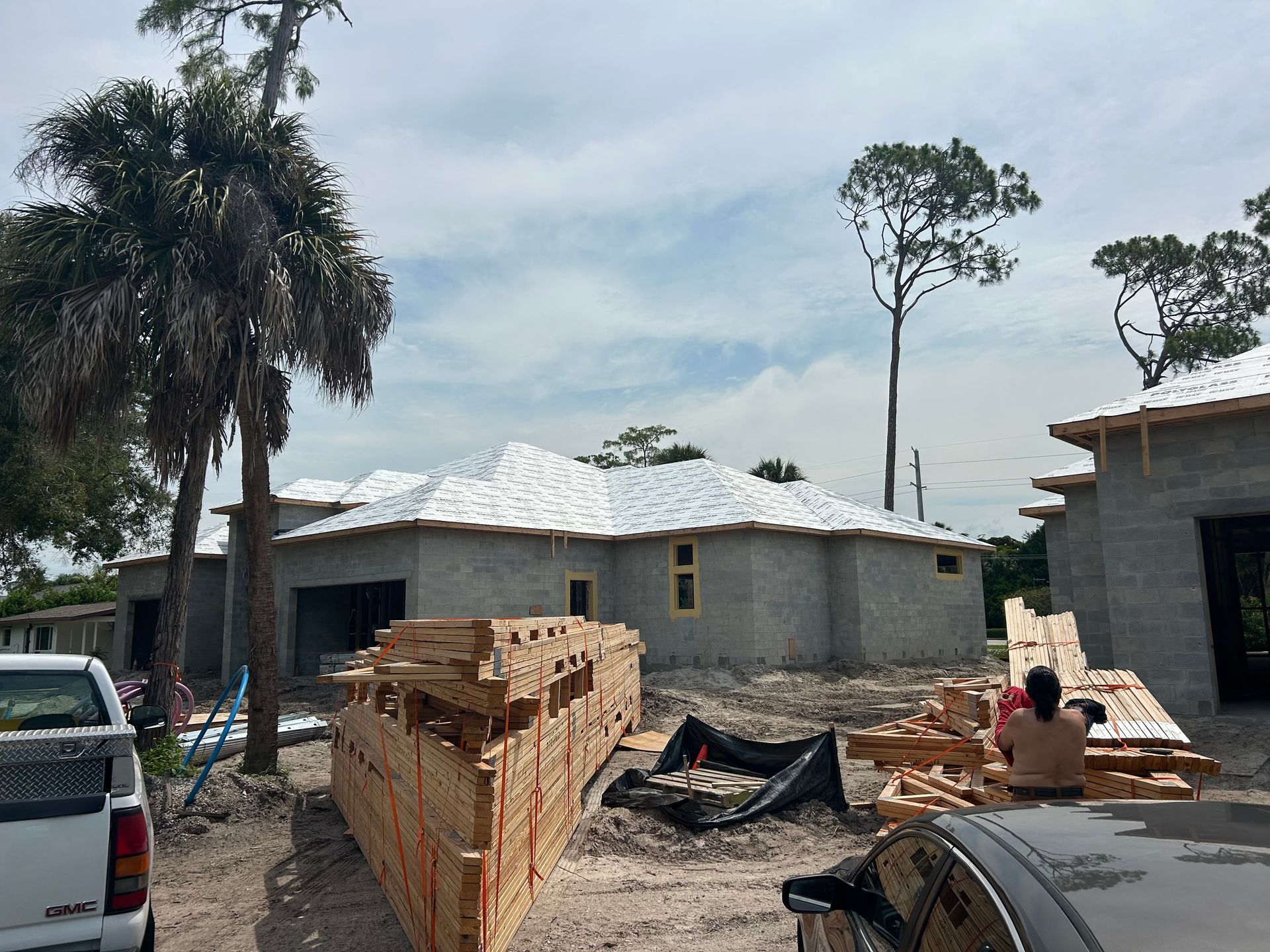 Partially built house with brick walls, rubble, and a person sitting beside a stack of concrete blocks