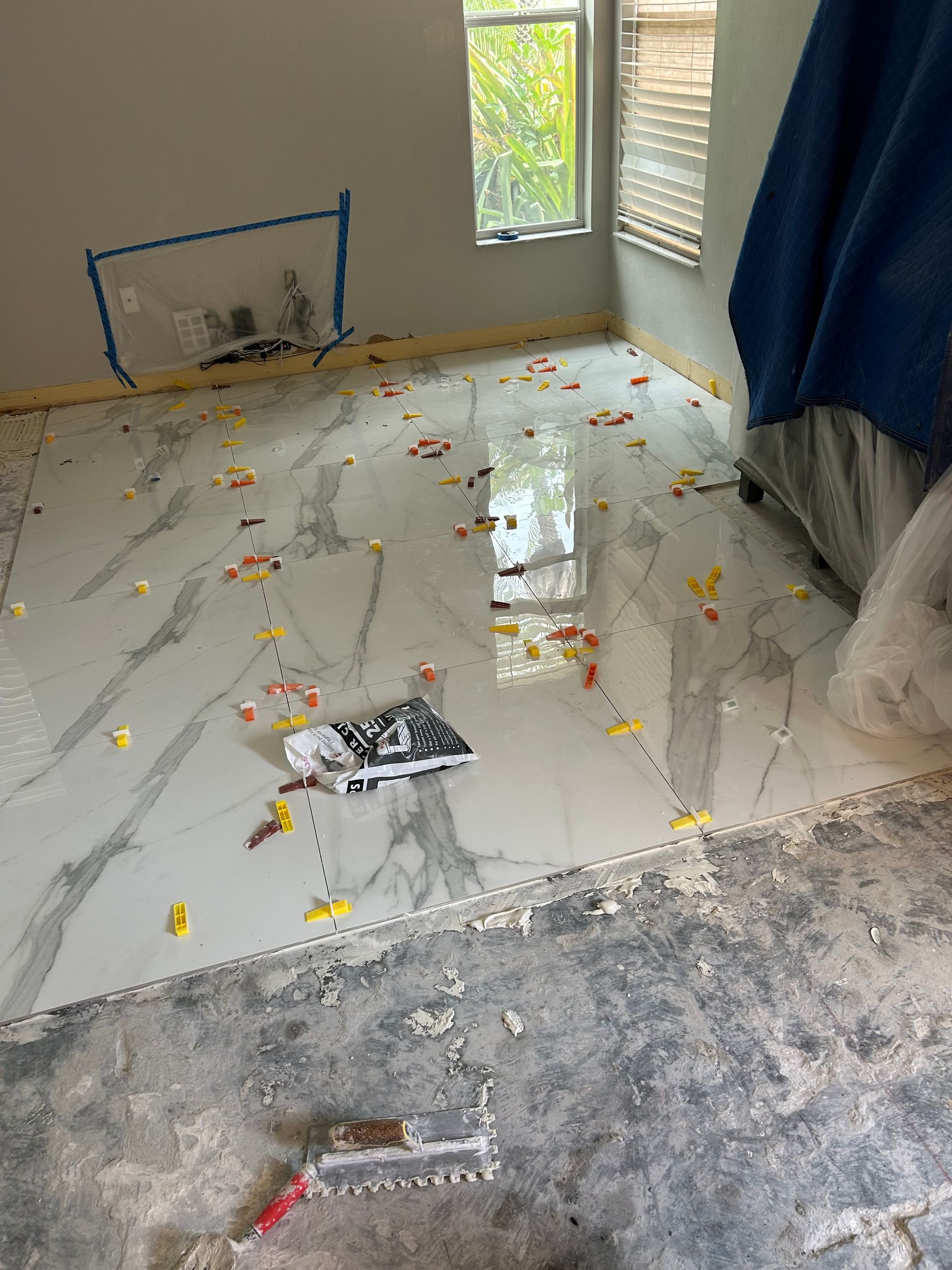 Flood-damaged room with wet tiled floor, debris, and a window letting in daylight.
