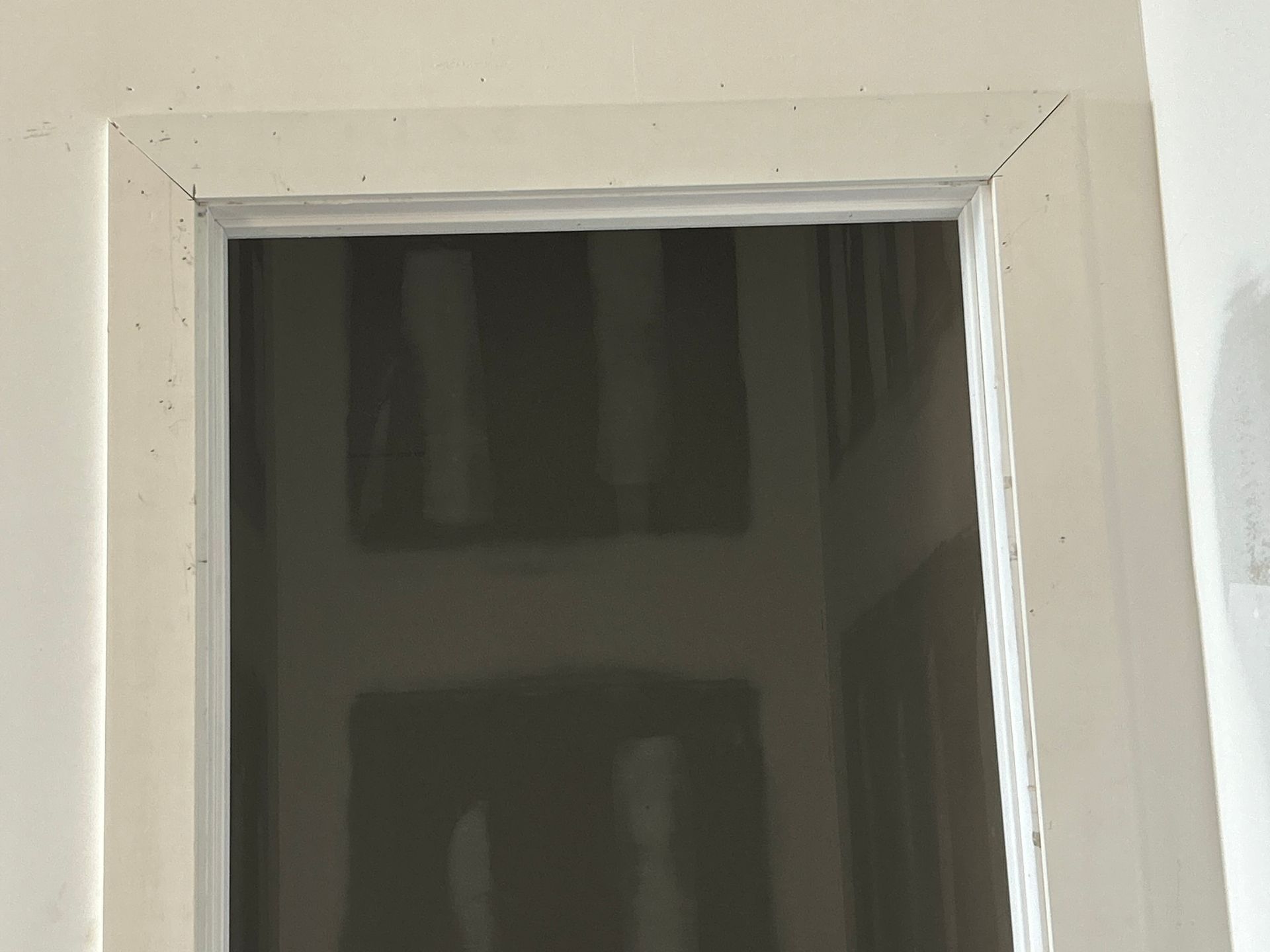 White-framed interior window with dark reflective glass panel