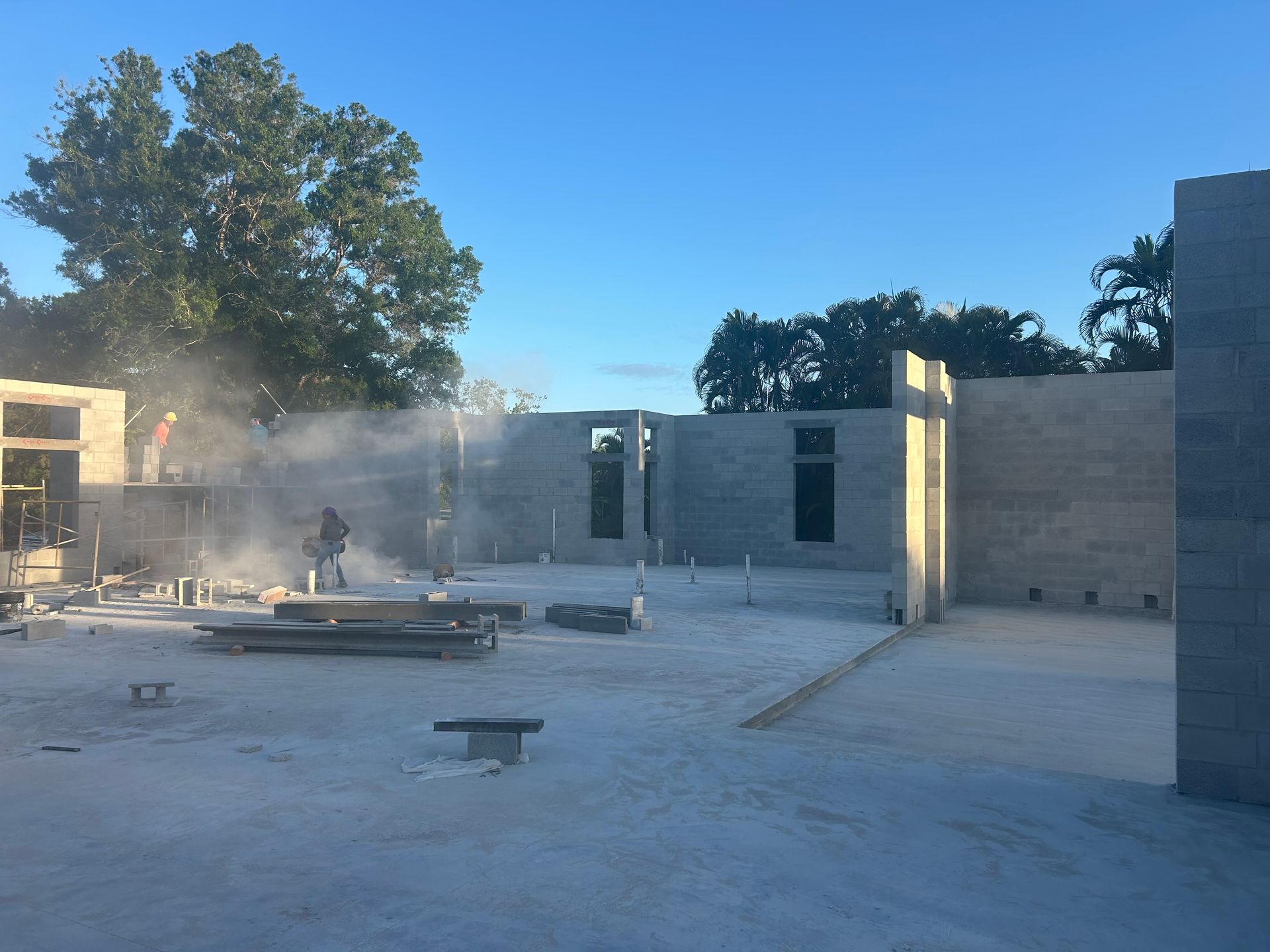 Dusty construction site with concrete walls and columns under a clear blue sky