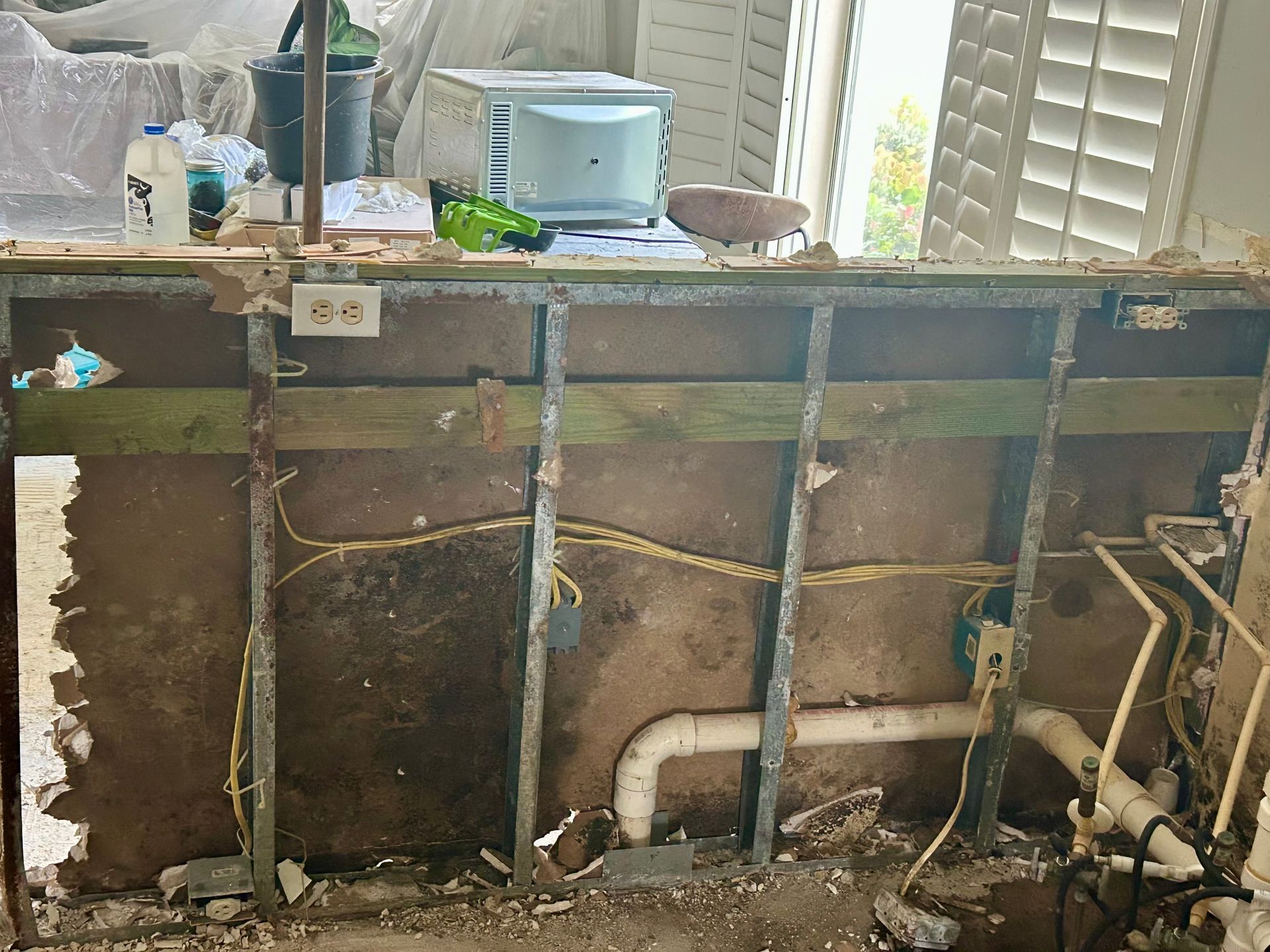 Exposed bathroom wall framing with pipes and wiring, showing renovation or repair work.