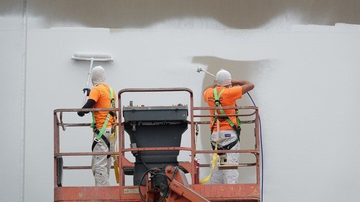 Two painters painting a white wall