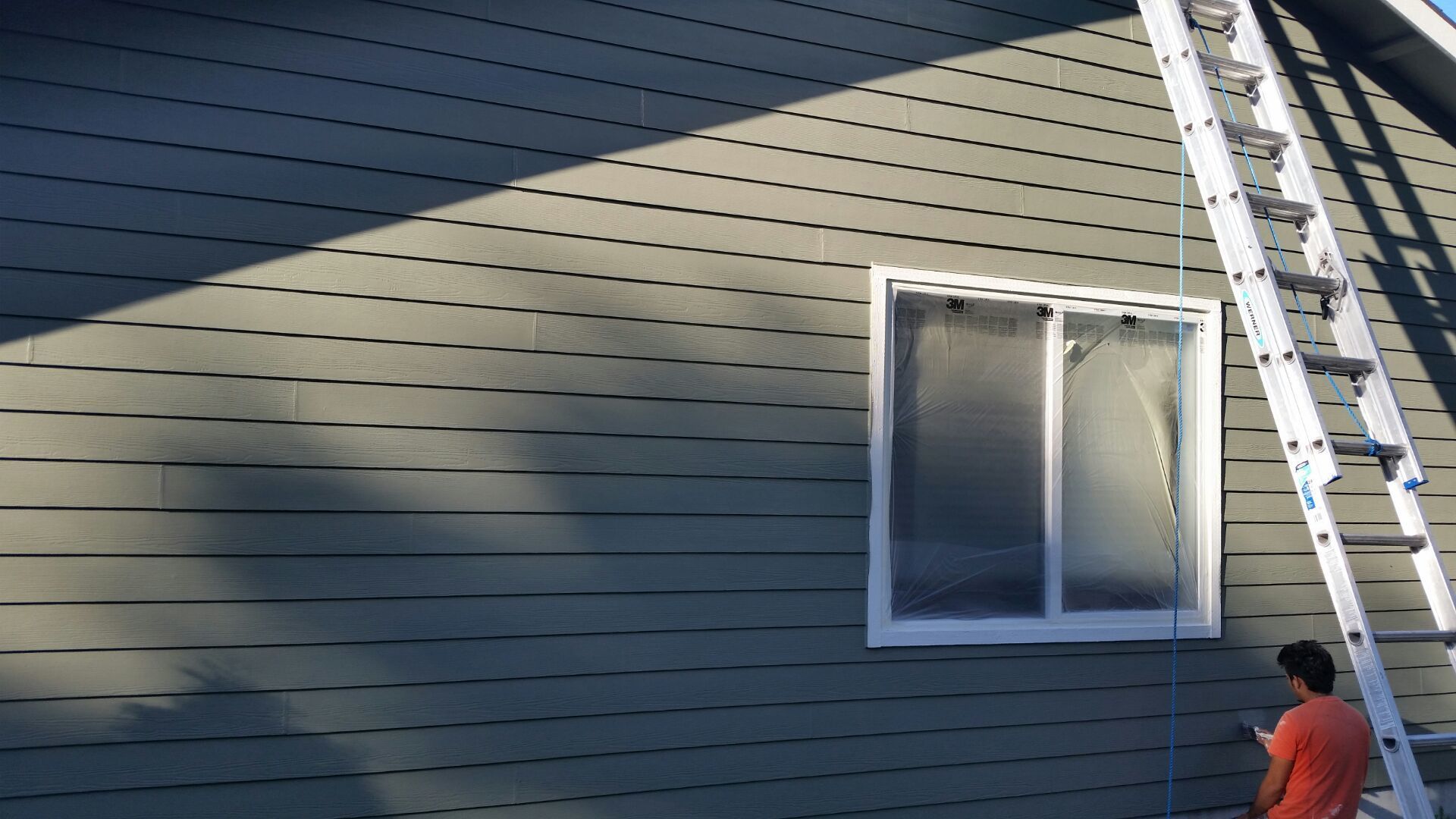 Man painting the siding of a house