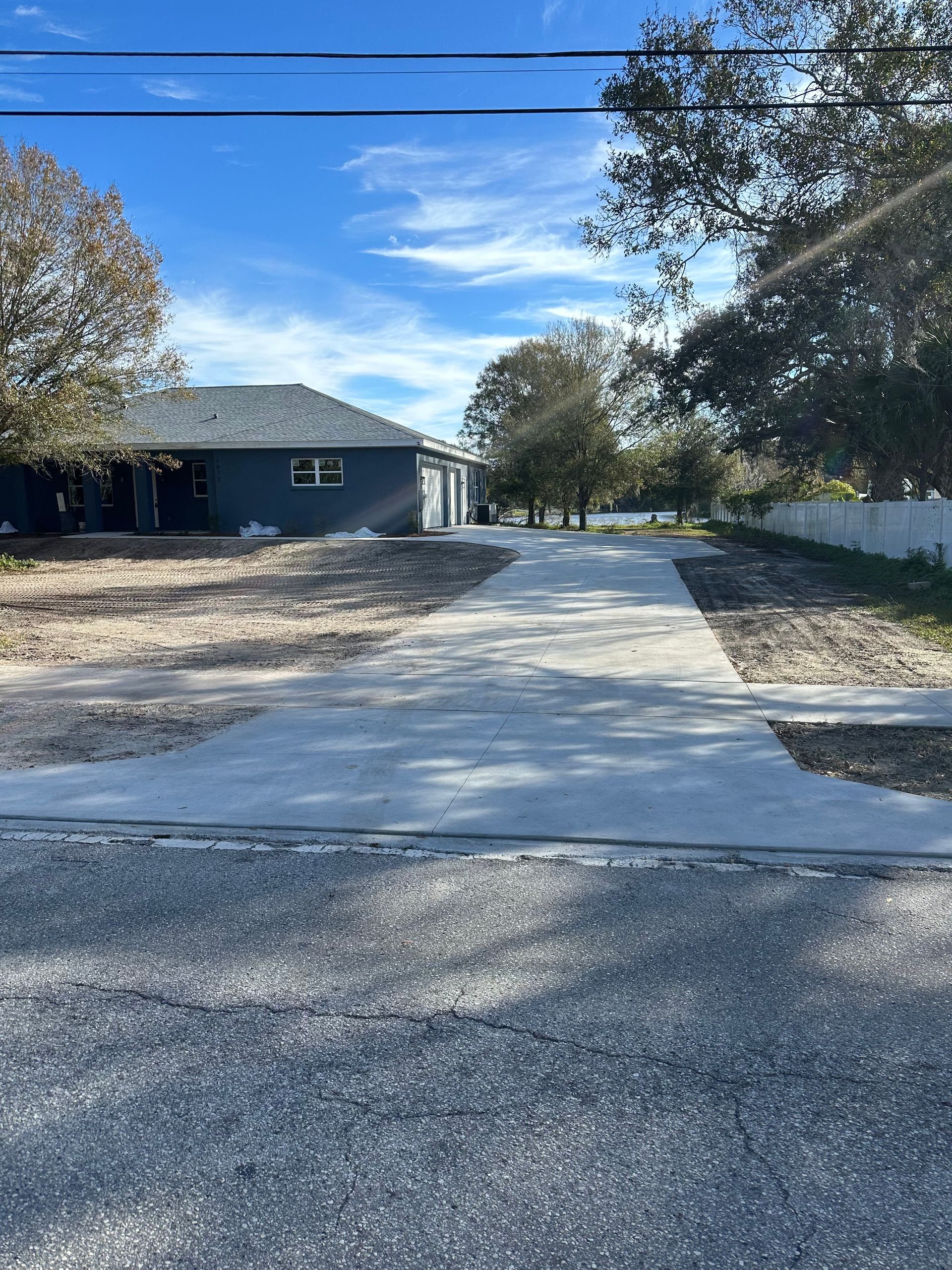 a concrete driveway leading to a house on a sunny day .