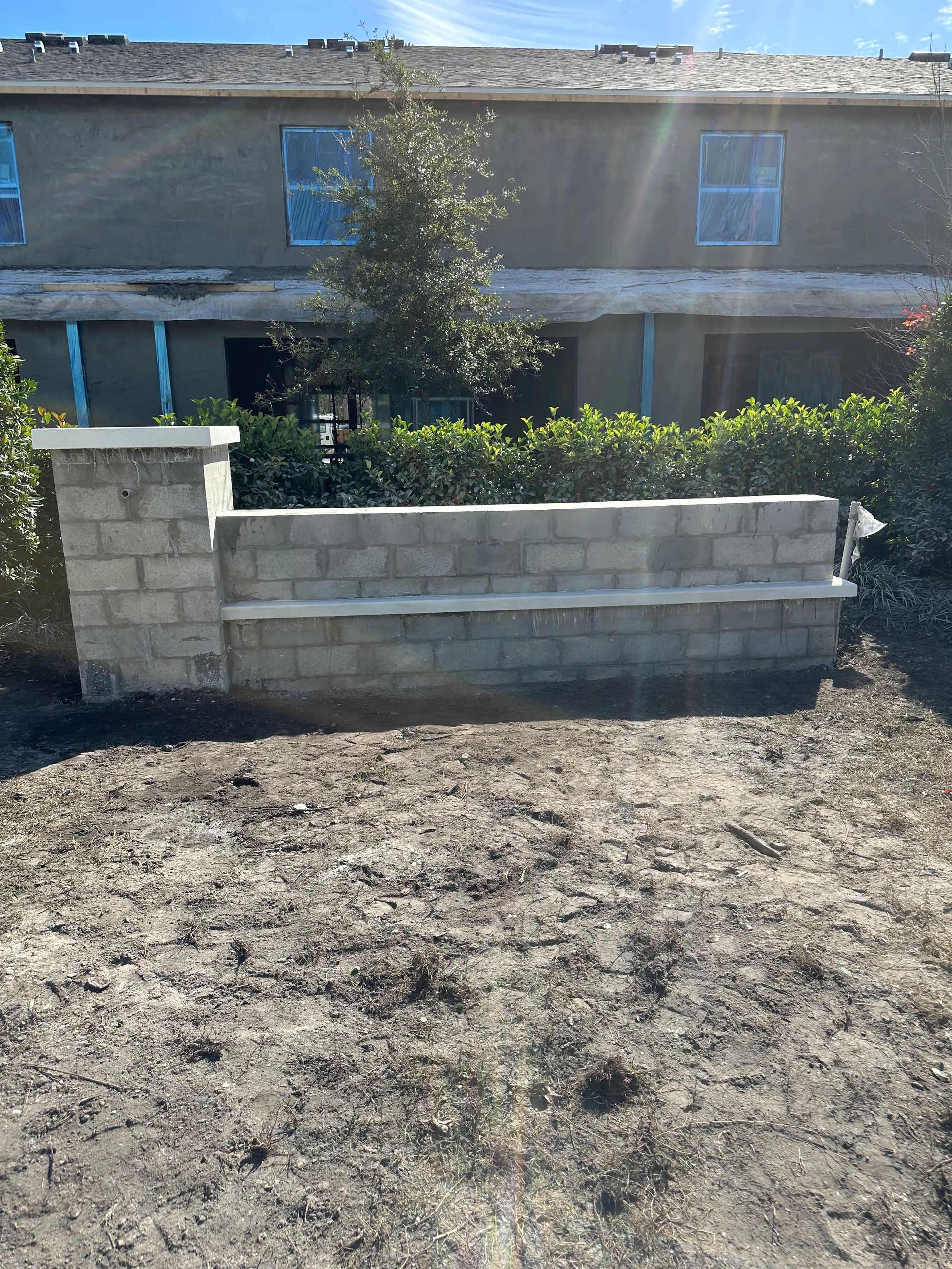 A brick wall is being built in front of a house.