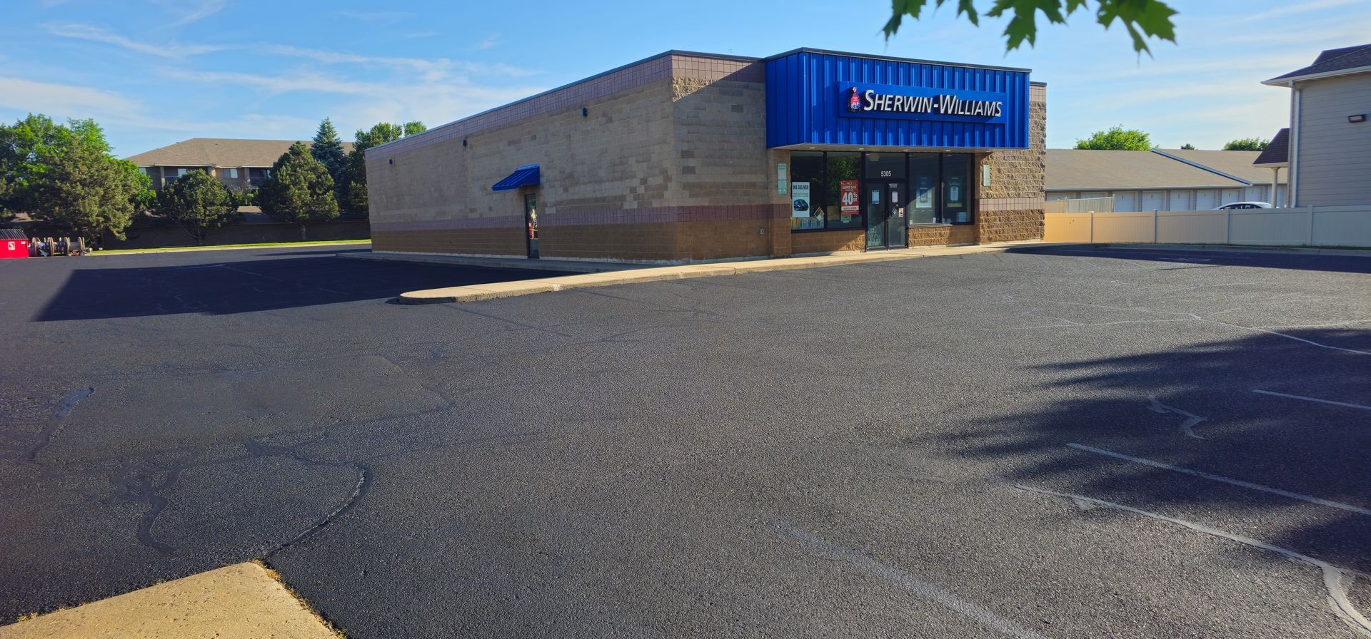 Storefront with a blue sign and empty parking lot on a sunny day