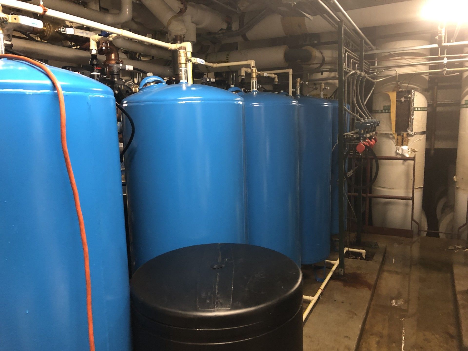 Blue industrial tanks in a utility room with pipes and equipment