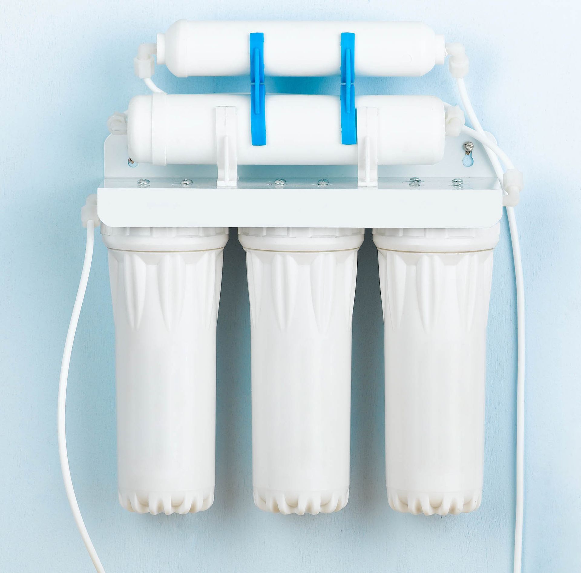 White water filtration unit with three hanging filter cartridges and blue tubing on a light background