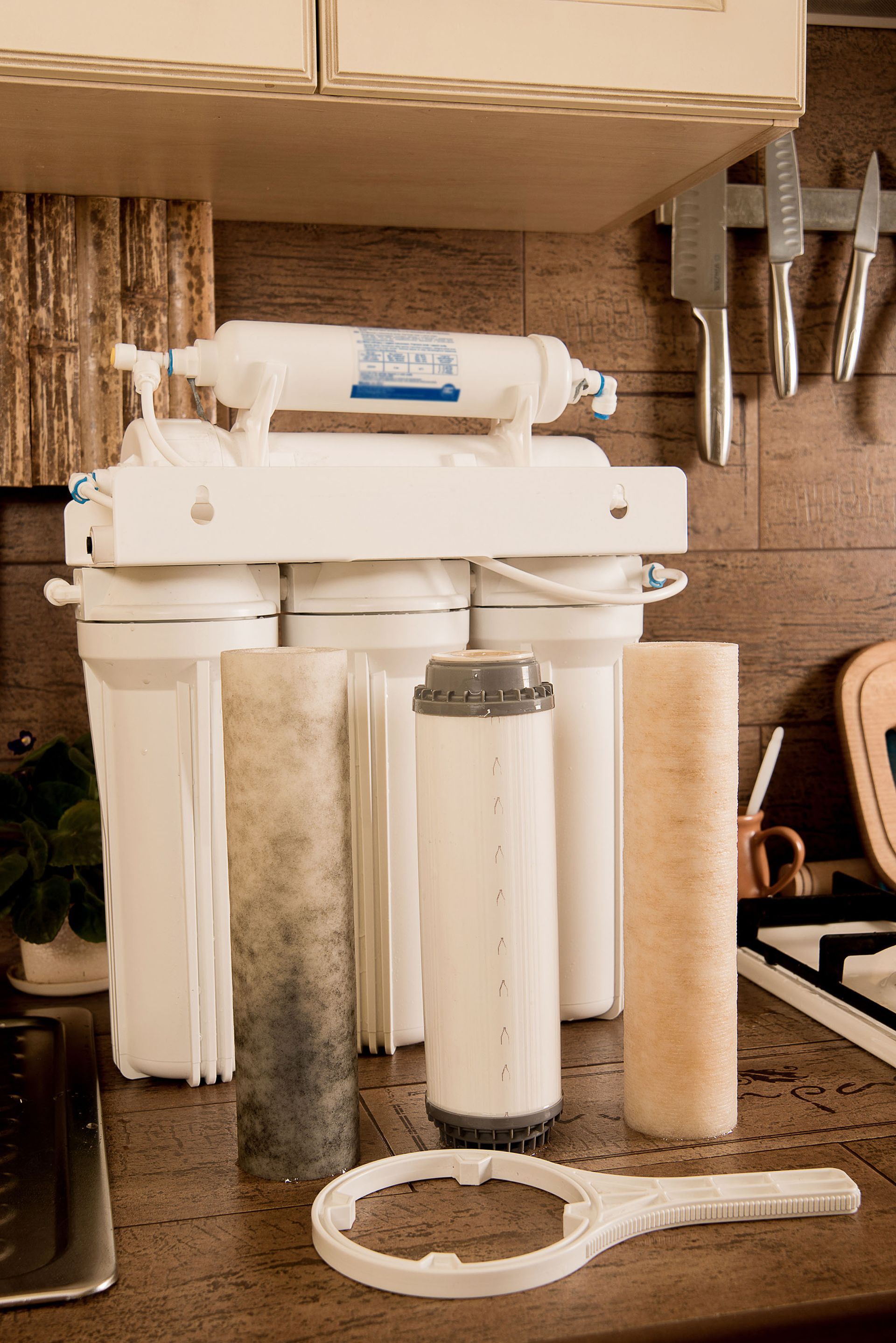 Under-sink water filtration system with white cartridges and tubing on a kitchen counter