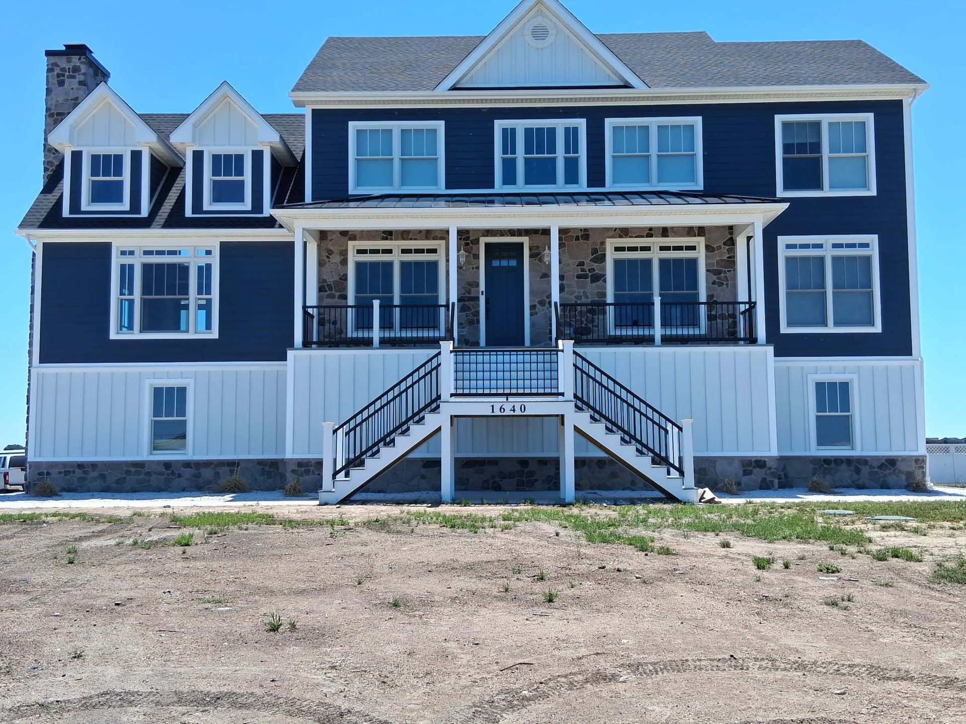 Two-story blue and white house with a front porch and central staircase under a clear sky