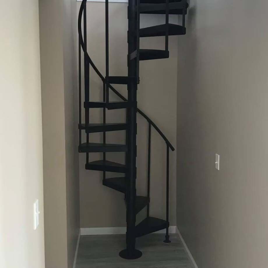 Black spiral staircase in a narrow hallway with gray walls and white trim