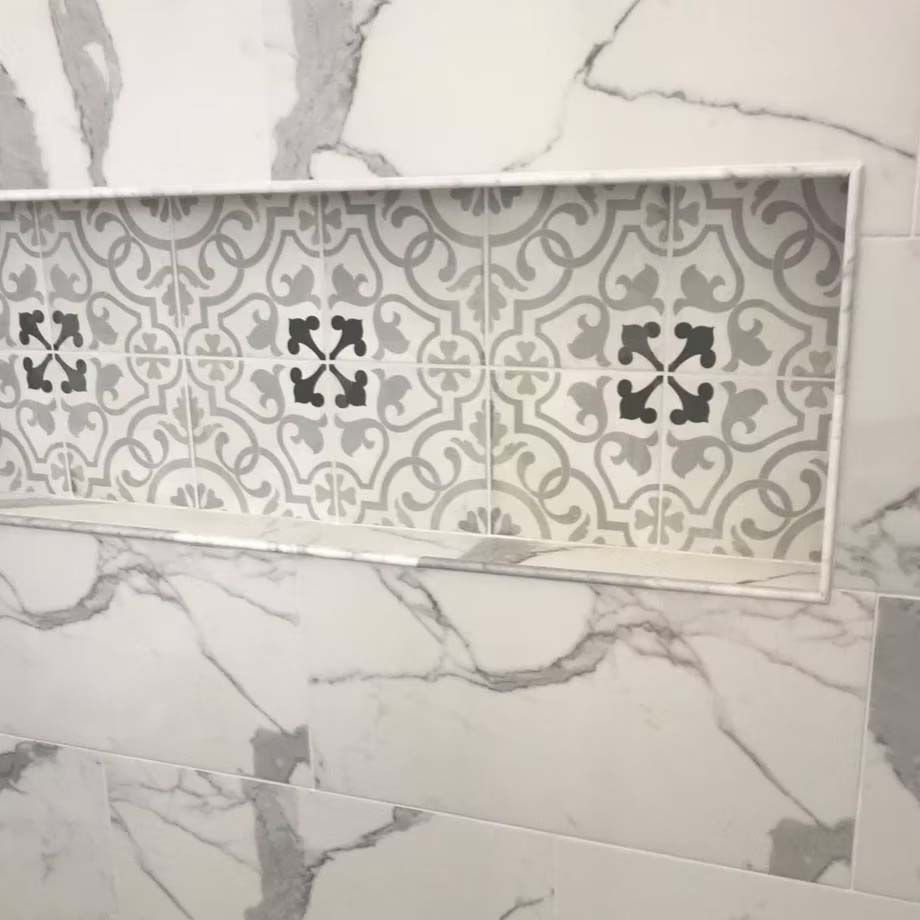 Decorative gray-and-white patterned tile inset in a marble-look wall.