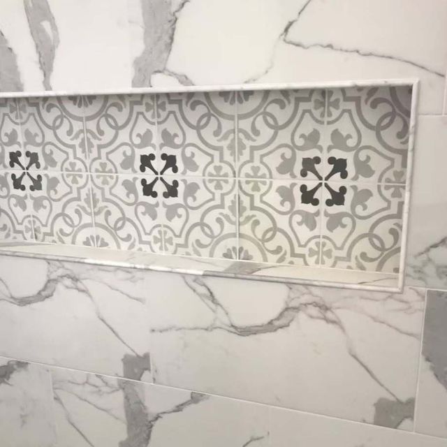Decorative gray-and-white tiled wall inset with patterned accent tiles in the center