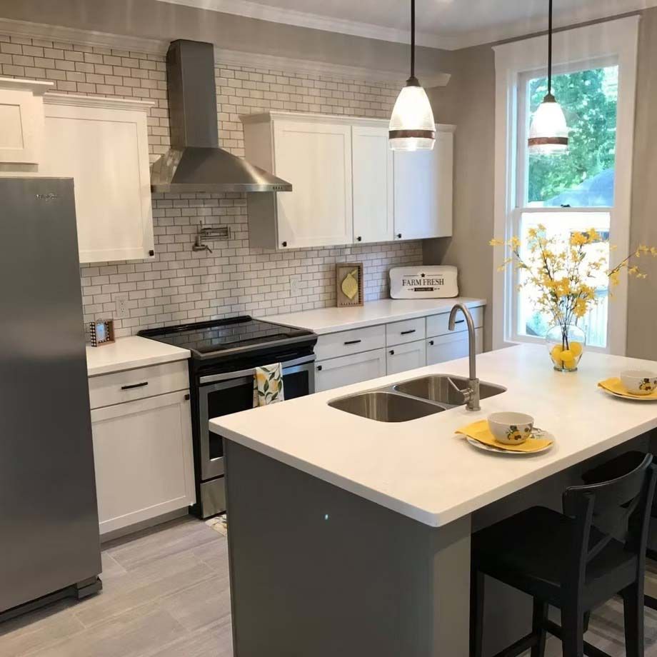 Bright modern kitchen with gray cabinets, white island, pendant lights, and a window by the sink