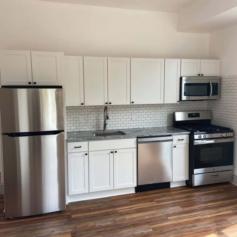 Modern white kitchen with stainless steel appliances and wood floor