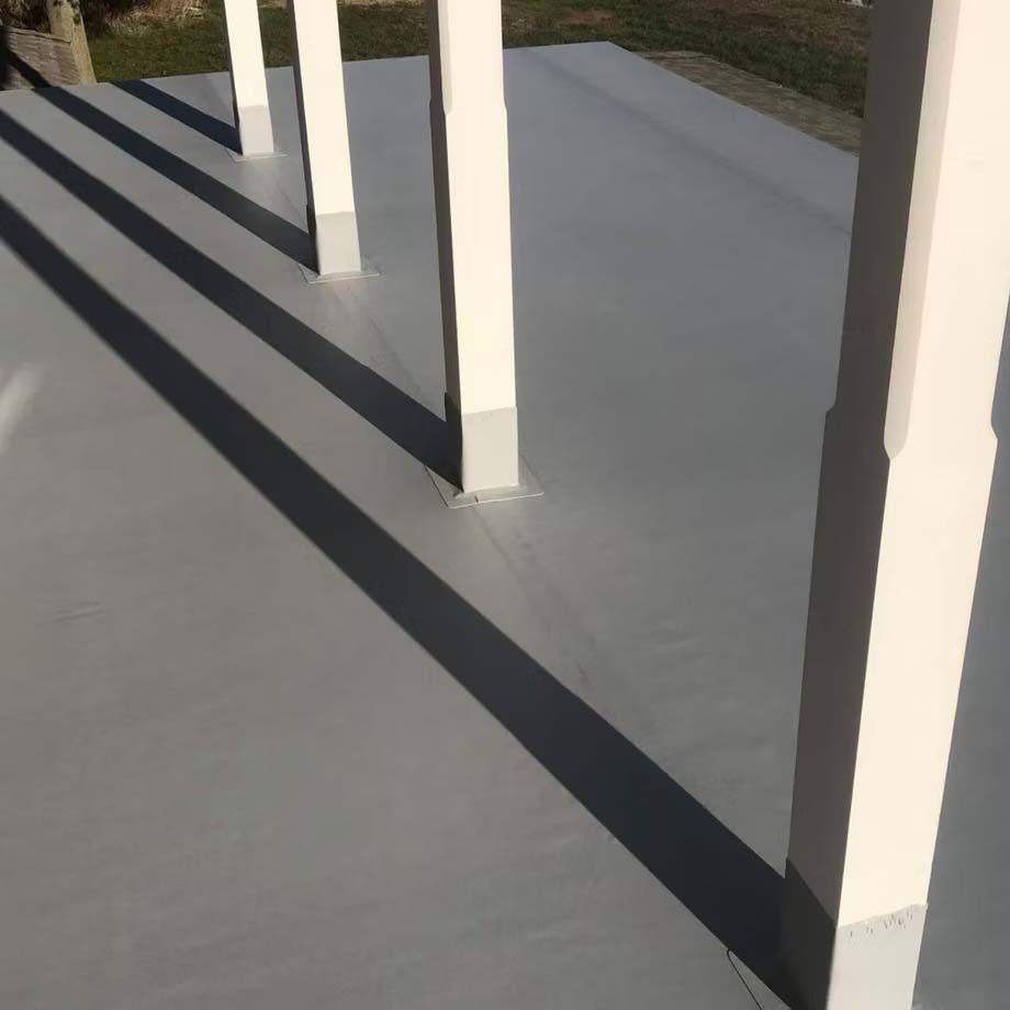 White porch columns casting long shadows on a gray concrete patio.