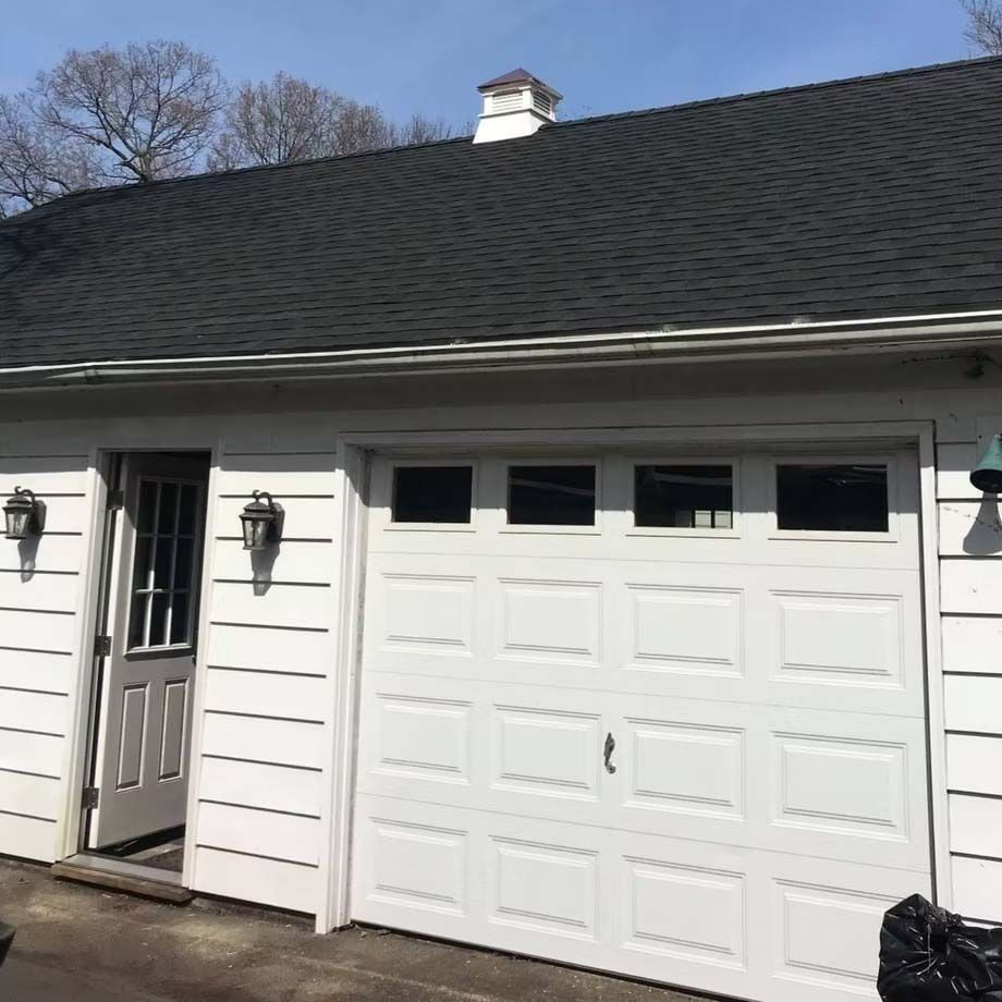 White garage with black roof and side door on a sunny day