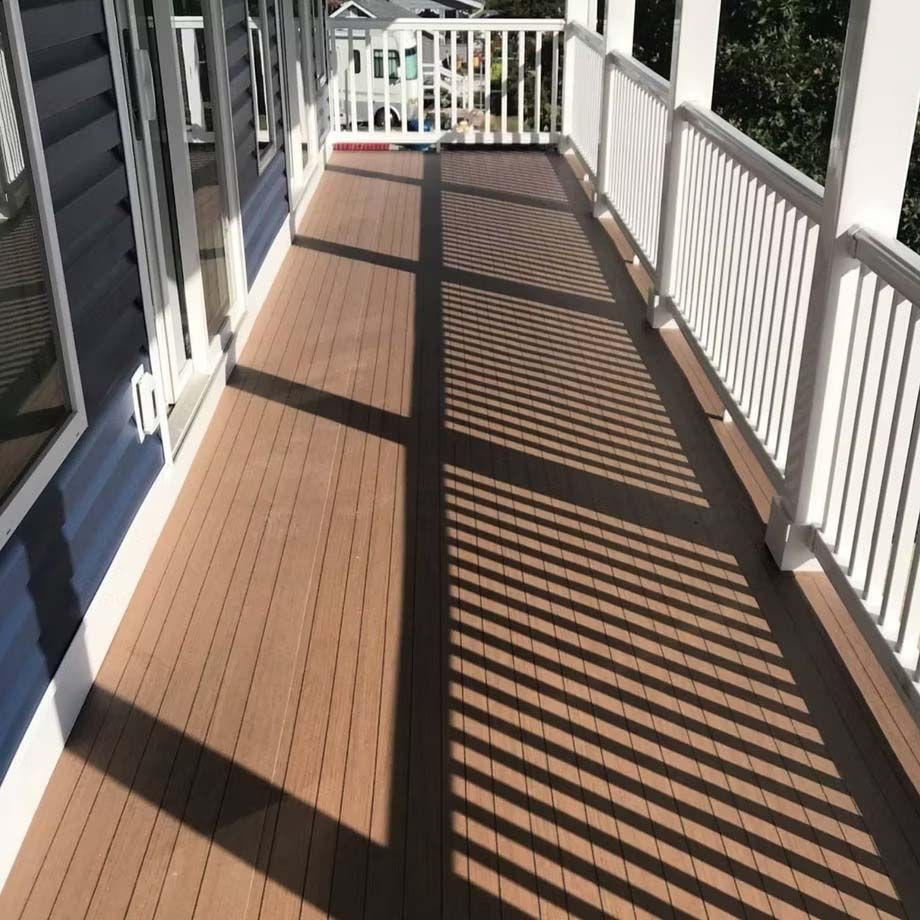 Sunlit porch with brown decking and white railings casting striped shadows