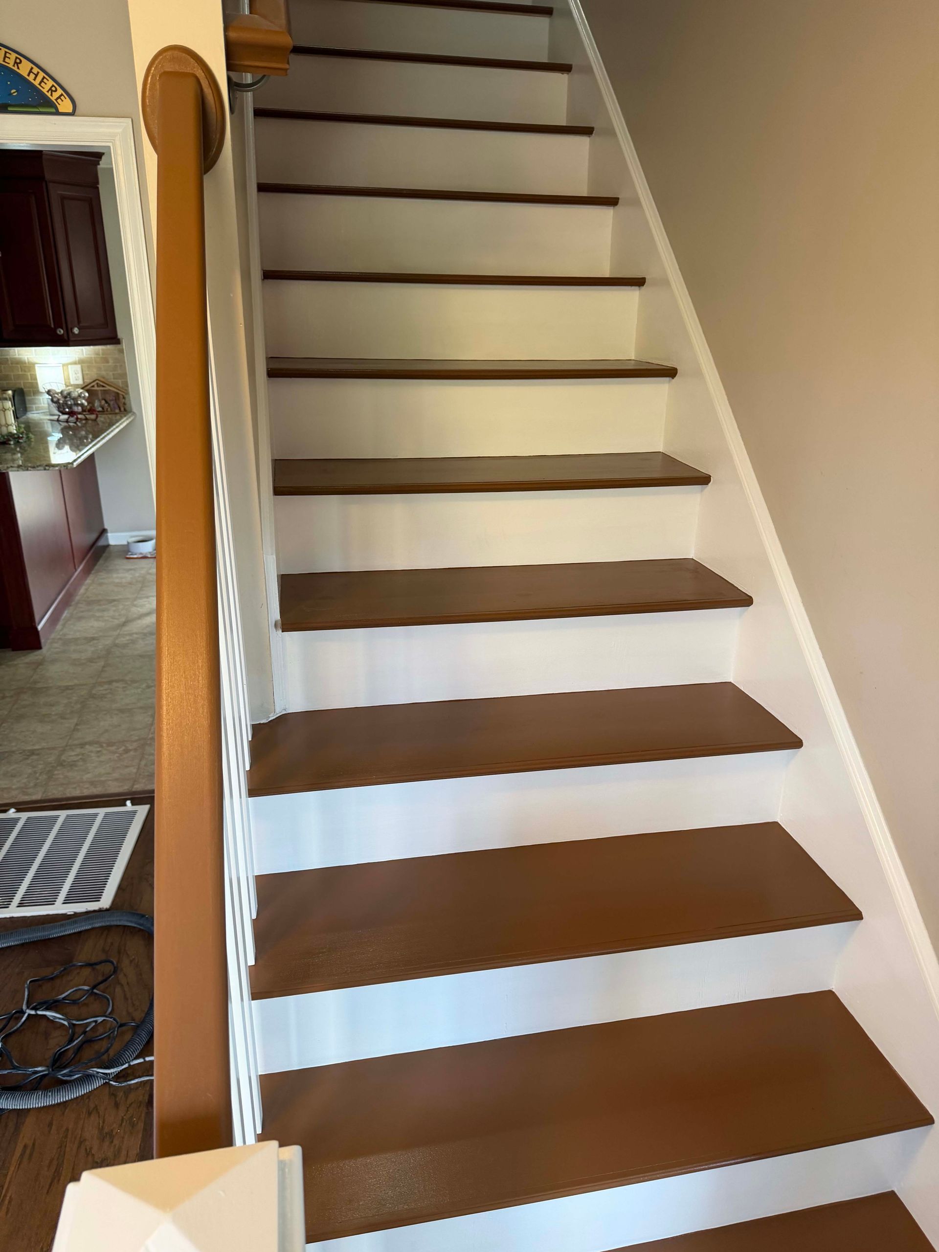 Indoor staircase with white railings and brown carpeted steps leading up to a hallway