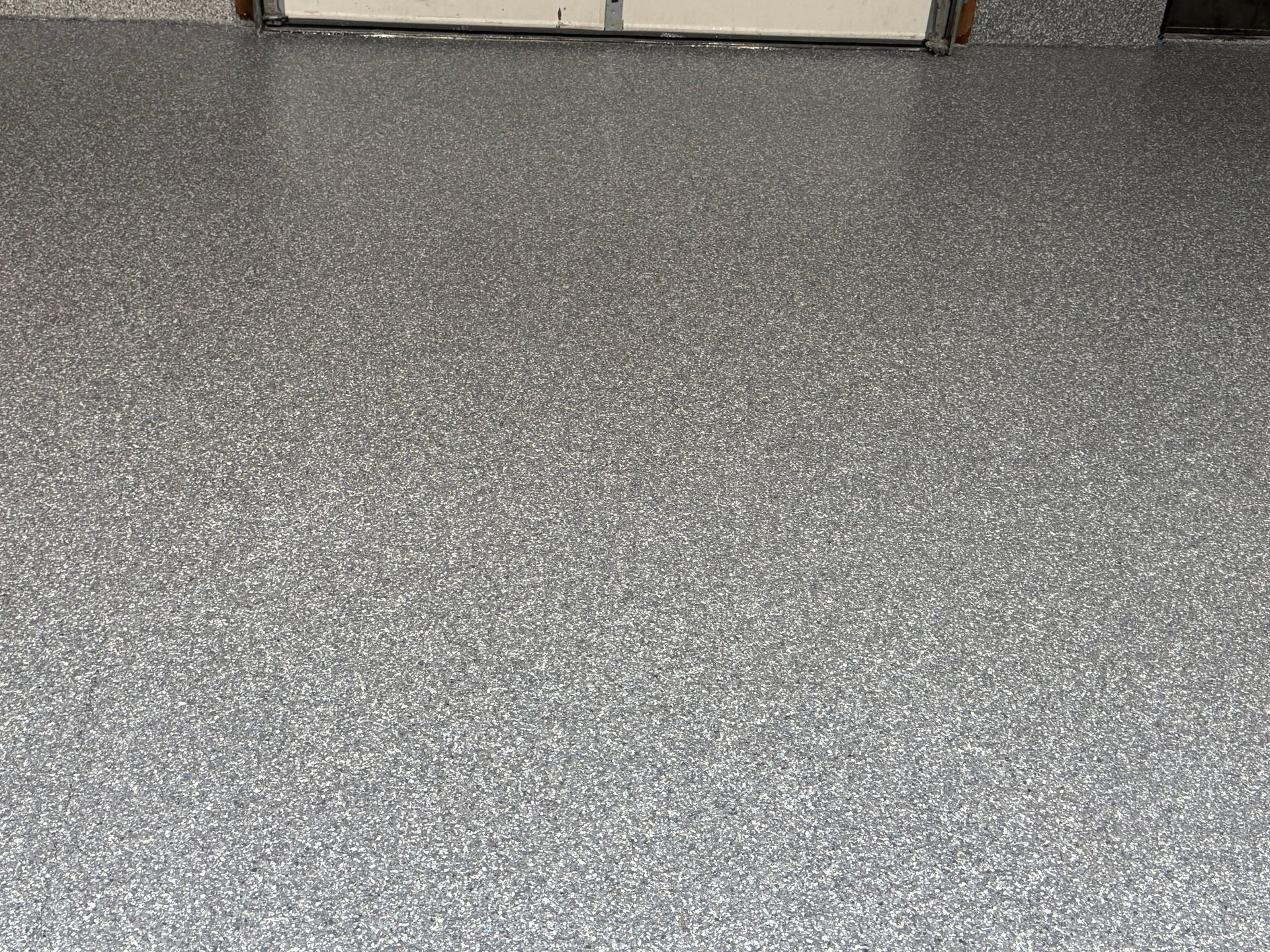 Gray speckled floor with a beige wall at the top edge
