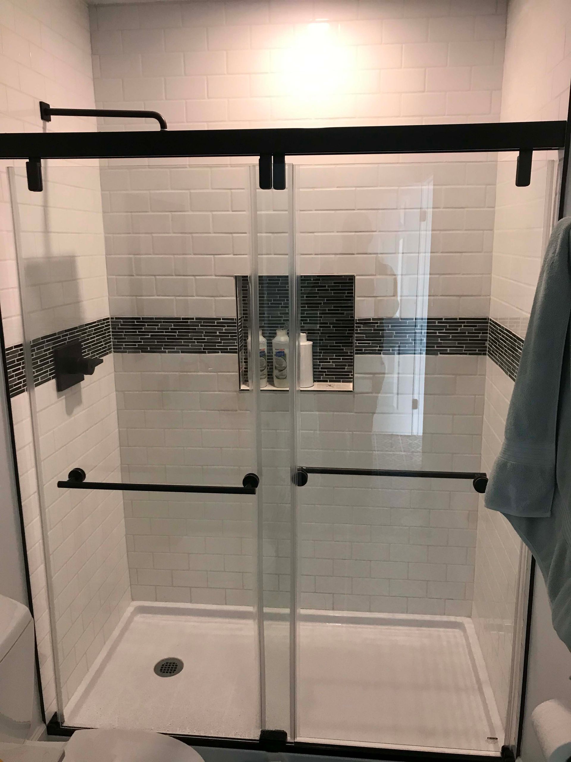 Modern glass shower enclosure with black hardware and white subway tile walls